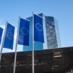 Four EU flags in front of the European Central Bank high-rise building