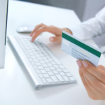 A person holding a bank card in front of a computer