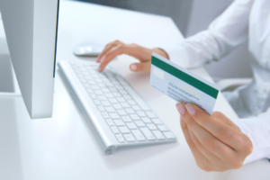 A person holding a bank card in front of a computer