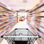 A supermarket trolley in the middle of a supermarket aisle.