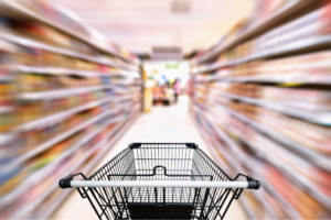 A supermarket trolley in the middle of a supermarket aisle.