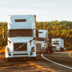 Three white trucks on a highway.