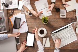 A group sitting around a table with laptops and business papers.