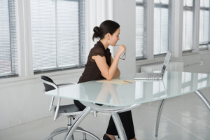 A business person sitting at a desk and looking into a laptop.